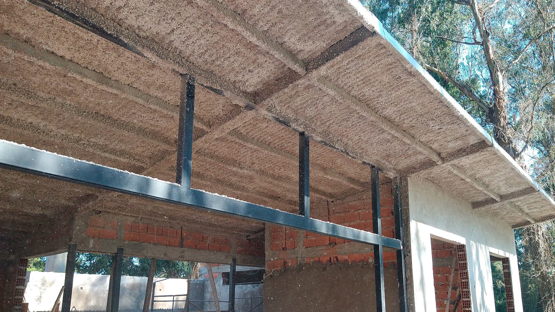 Techo de gimnasio con celulosa proyectada como aislamiento térmico y acústico.